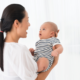 Shows a woman holding a baby in front of her while she sings to it.