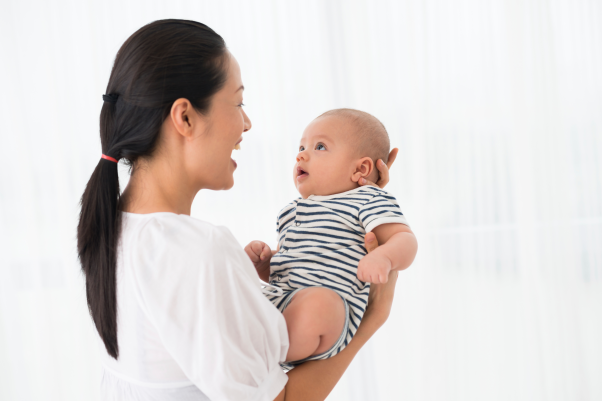 Shows a woman holding a baby in front of her while she sings to it.