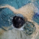 Shows a young boy in a pool face down in the water