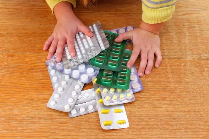 Shows a baby's hands on top of various pill packets