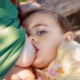 The image shows a baby in a yellow outfit breastfeeding from her mother's breast